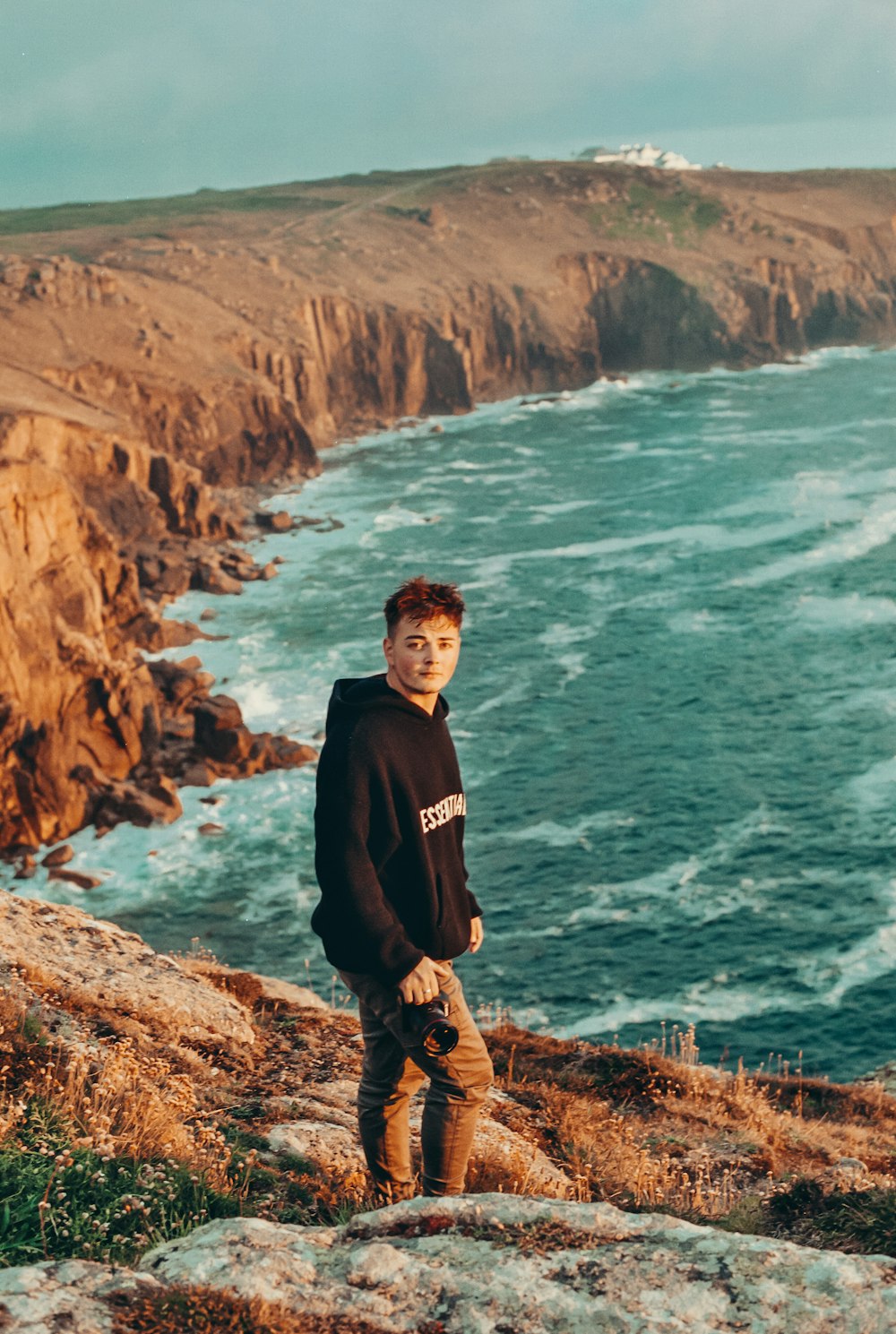 a man standing on top of a cliff next to the ocean