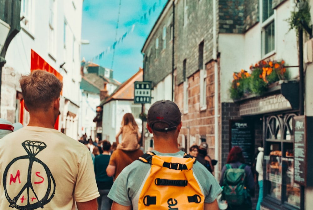 a couple of men walking down a street next to tall buildings