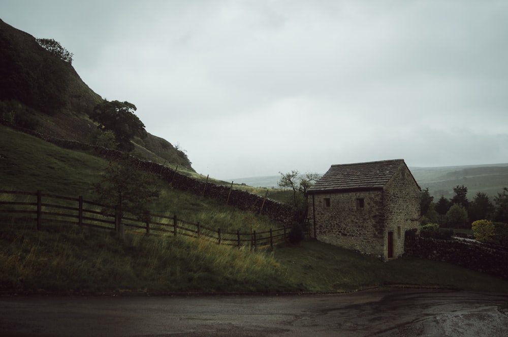 a stone building on a hill with a fence around it