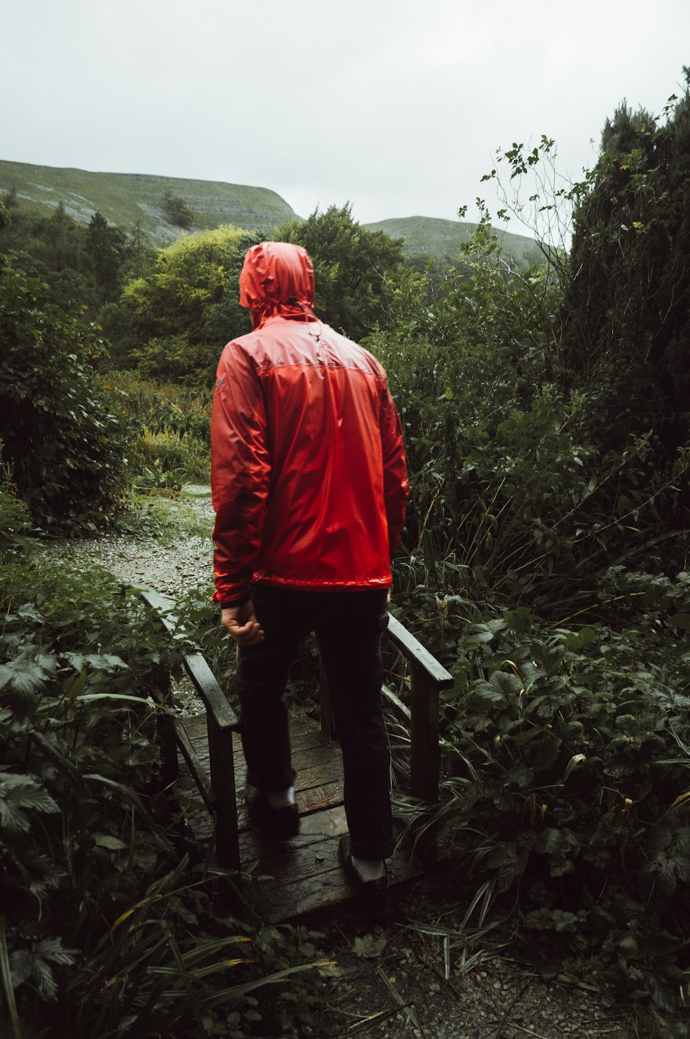 a man in a red jacket walking up a wooden walkway
