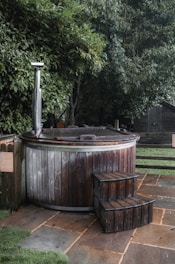 a wooden hot tub sitting on top of a lush green field