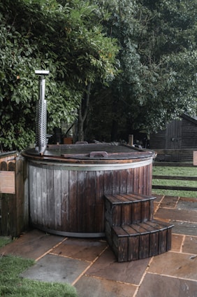 a wooden hot tub sitting on top of a lush green field