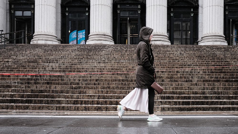 a woman walking down the street in front of a building