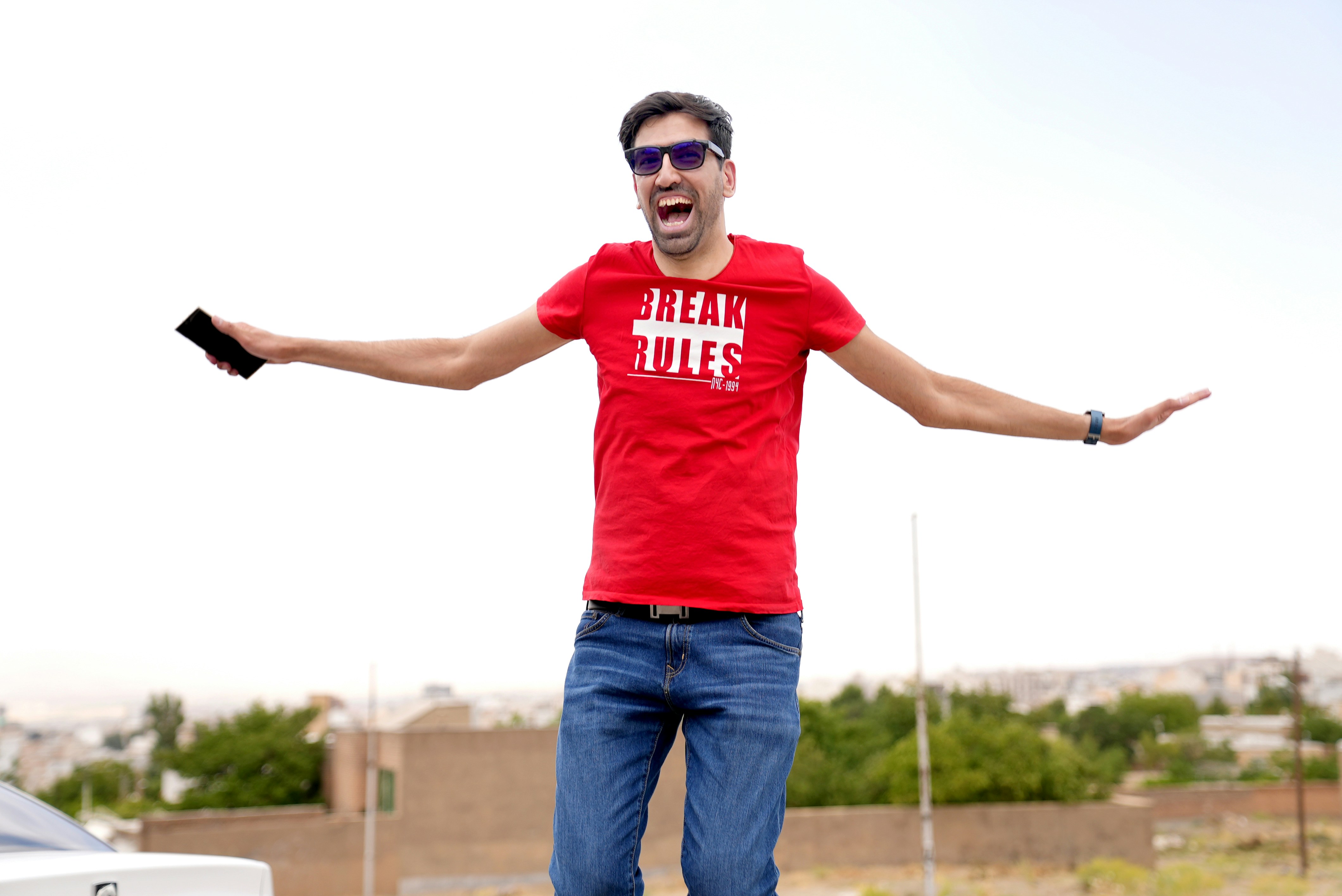 a man in a red shirt is standing on a skateboard