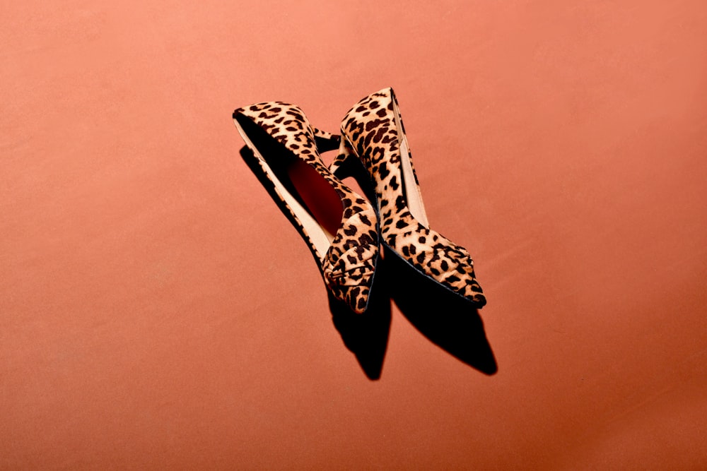 a pair of leopard print shoes on a pink background