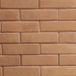 Close-up of a craftsman carefully laying bricks on a warm beige wall.