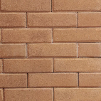 A close-up of skilled hands laying bricks on a rustic stone wall under bright natural light.