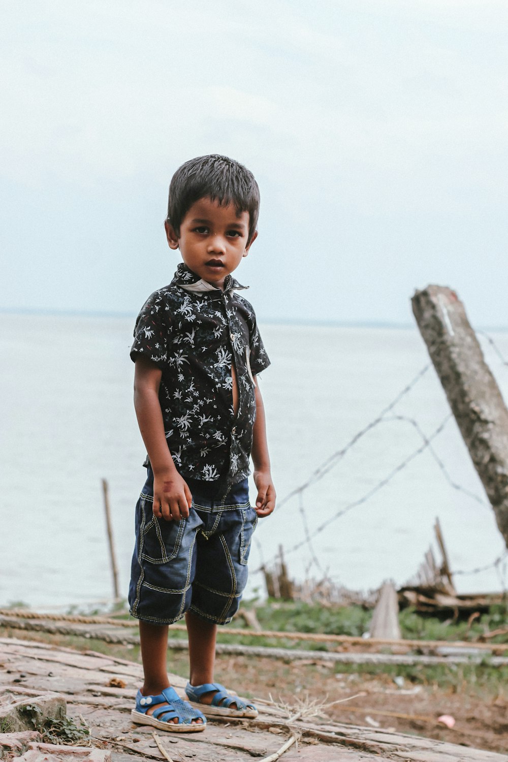 a young boy standing on a beach next to the ocean