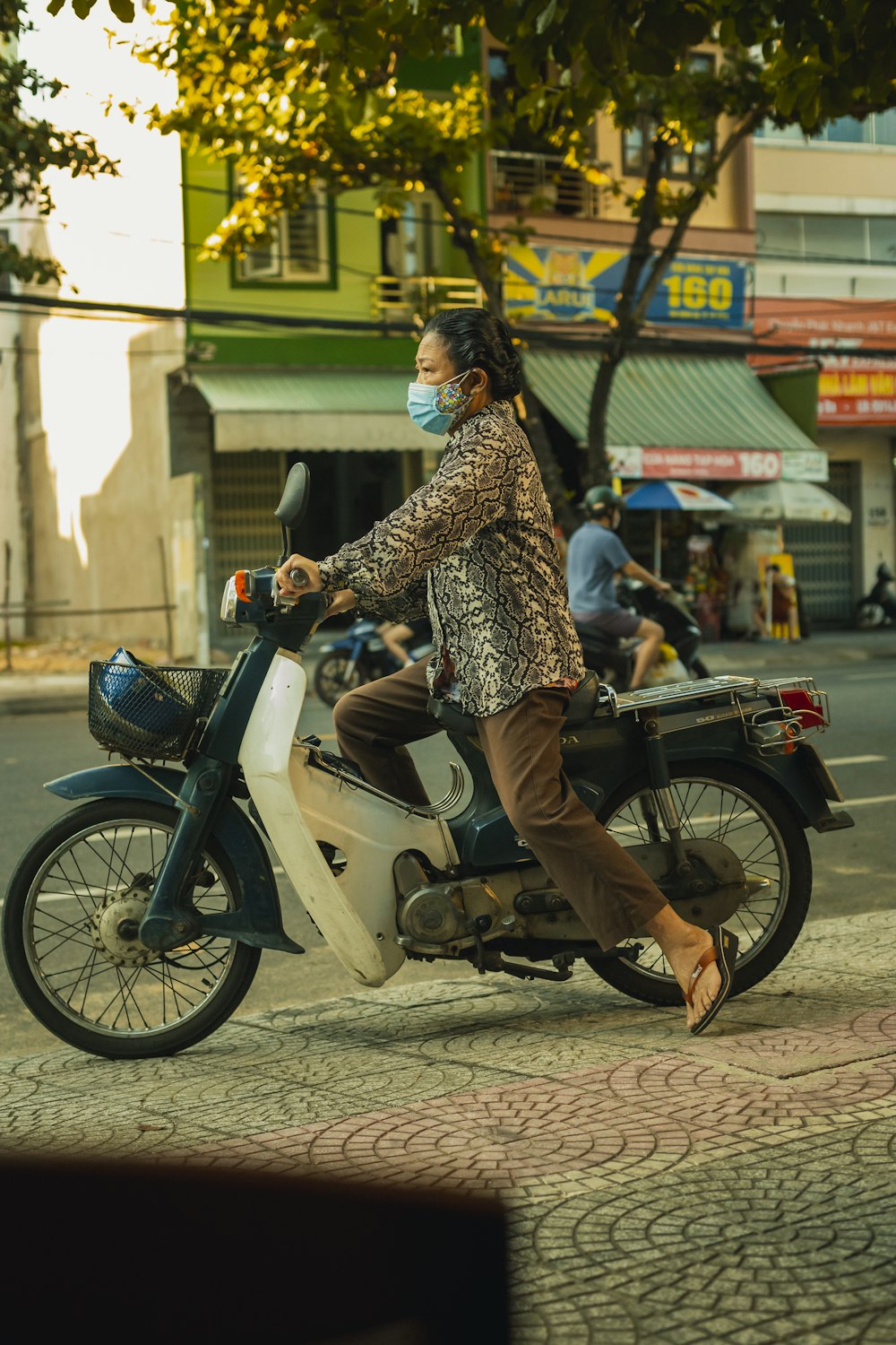 a woman wearing a face mask riding a scooter