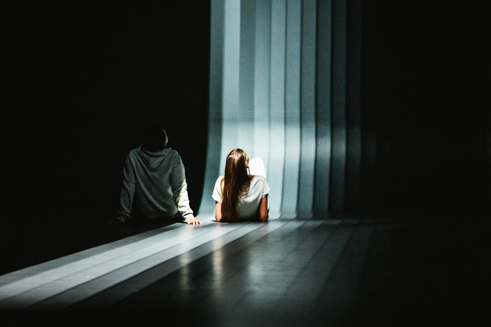 a man and a woman sitting on the floor in the dark