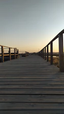 A skilled craftsman carefully assembling a wooden boardwalk under bright sunlight.