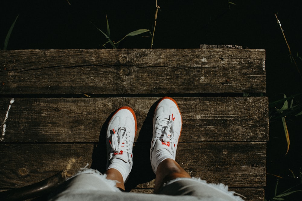 a person's feet wearing white and orange sneakers