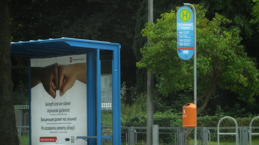 a blue and white bus stop sitting next to a forest