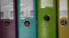 a row of colored binders on a shelf