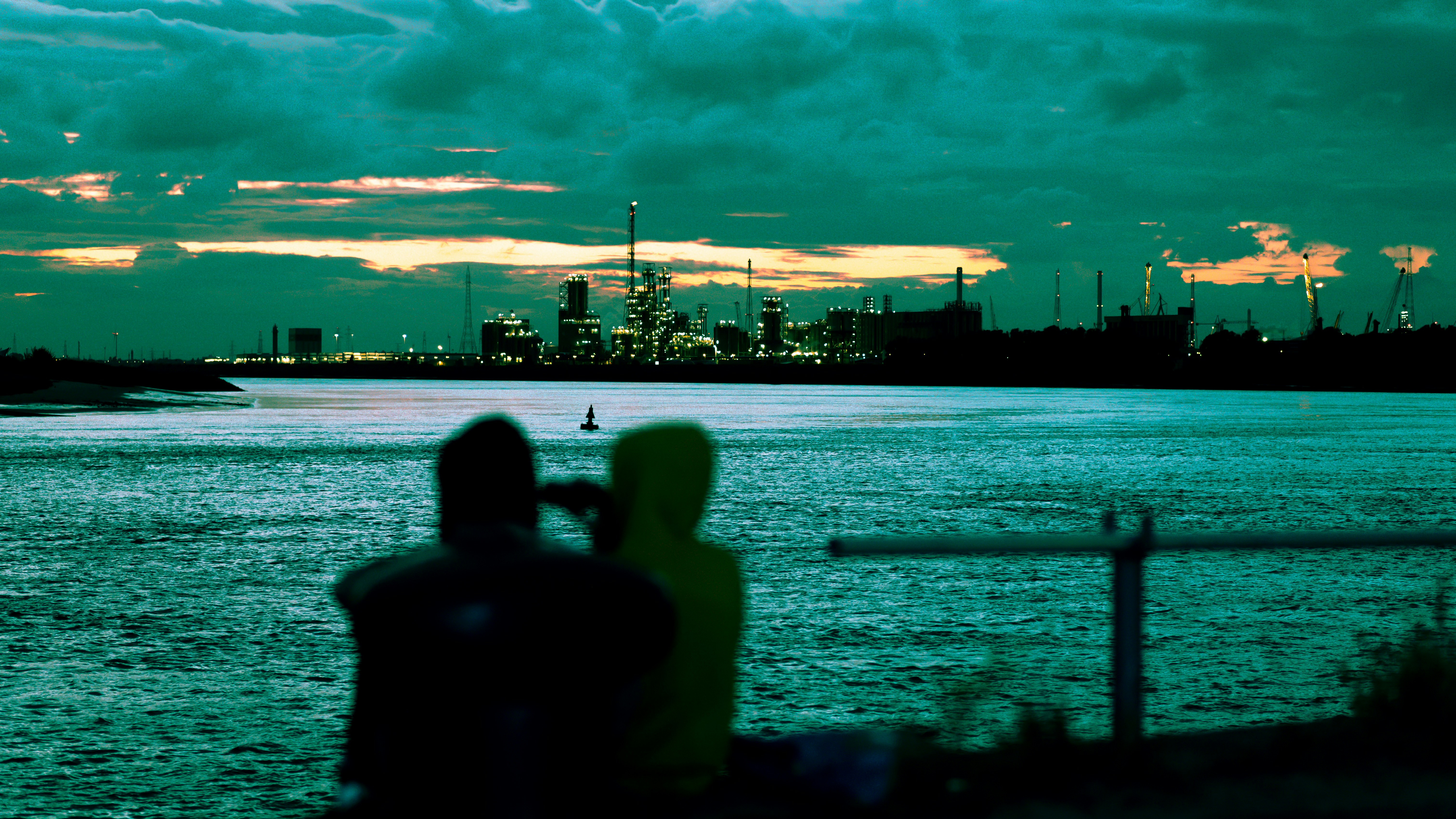 two people sitting on a bench looking out over the water