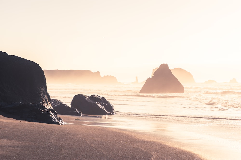 a sandy beach with a rock formation in the background