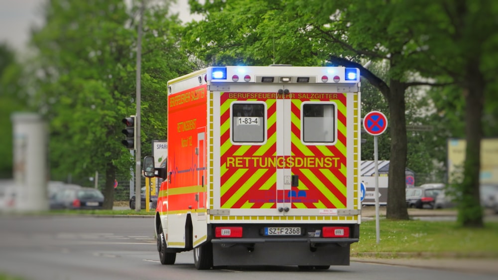 a red and yellow emergency truck driving down a street