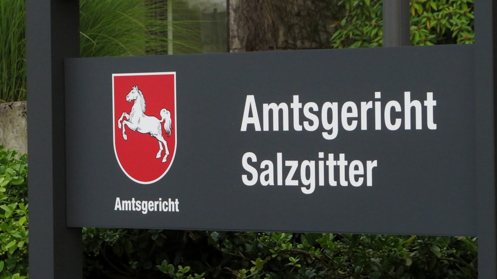 a black sign with a red and white horse on it