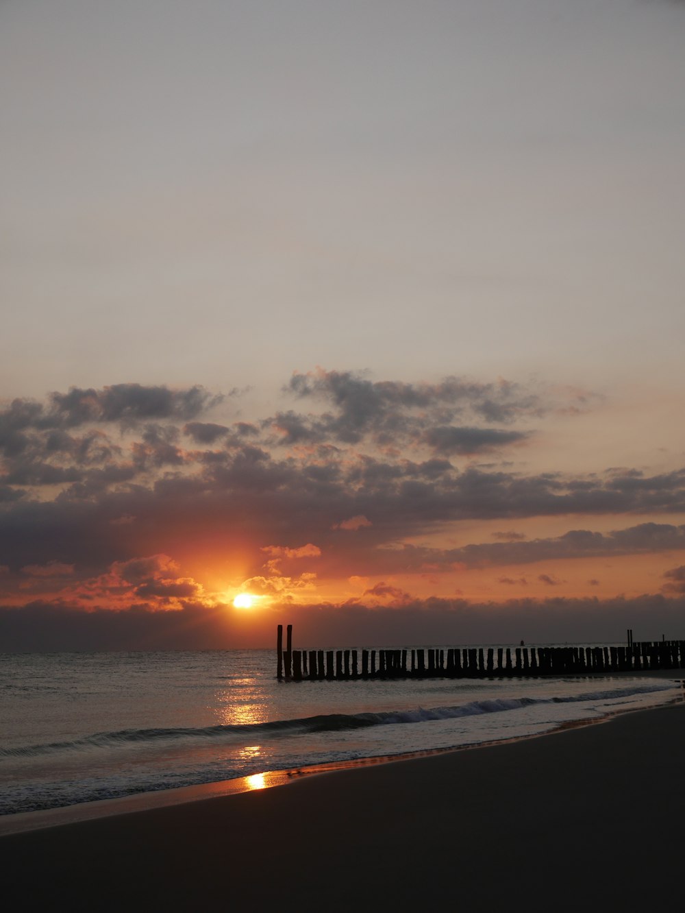 the sun is setting over the water at the beach