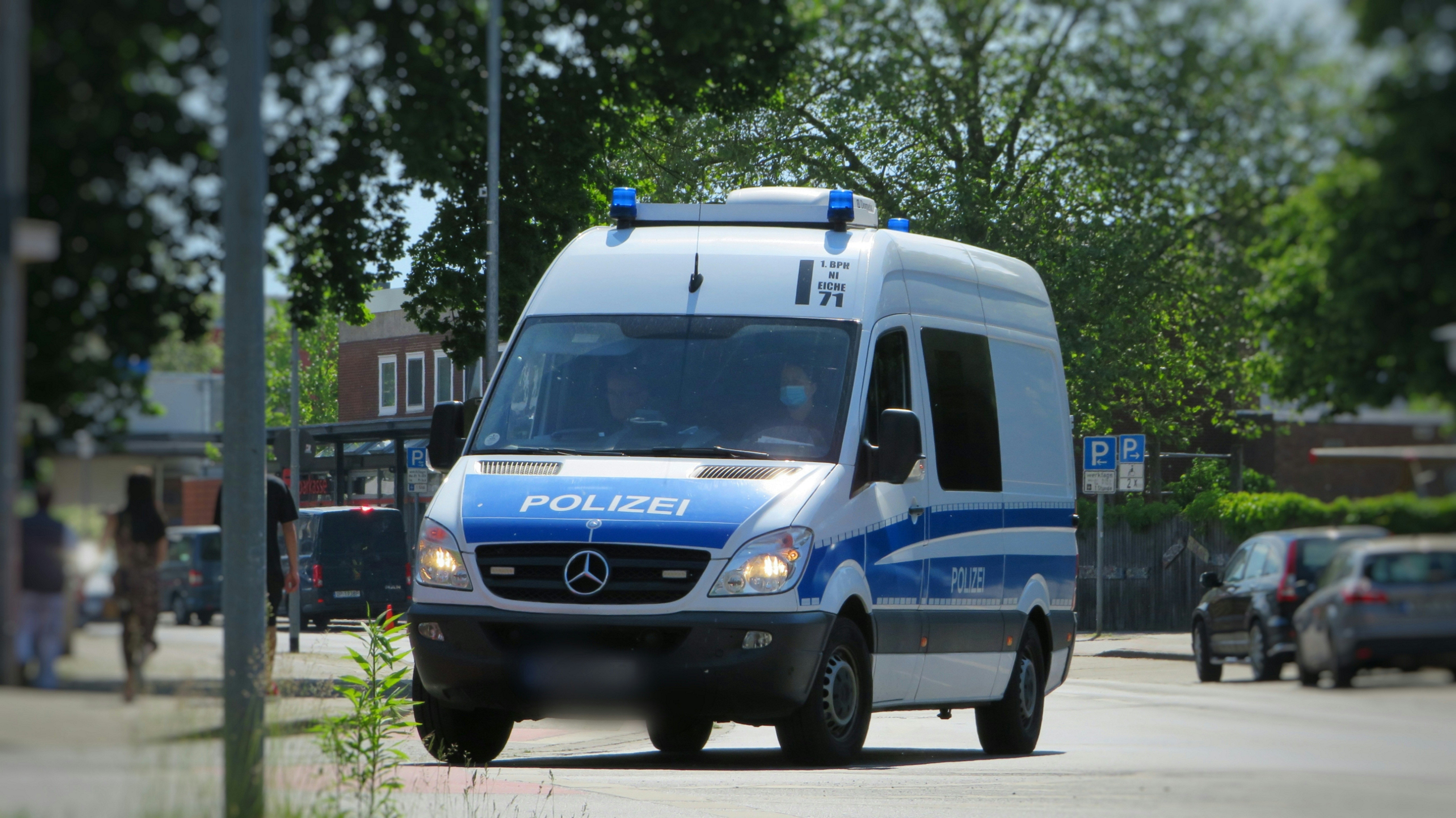 a blue bus driving down a street next to a car