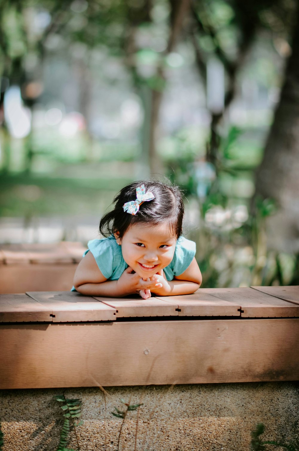 a little girl laying down on a wooden bench