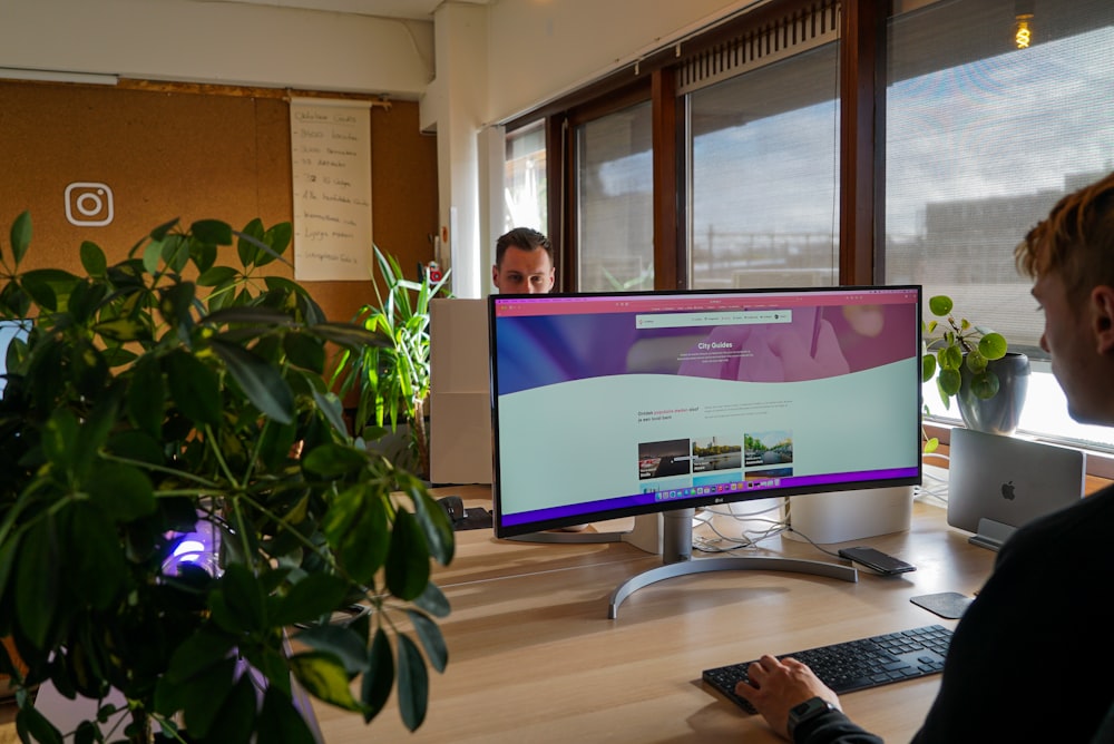 a man sitting at a desk in front of a computer monitor