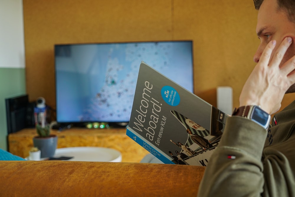 um homem sentado em um sofá lendo um livro