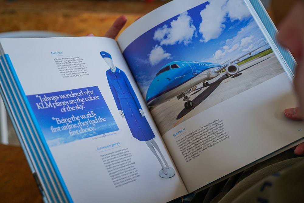 a person holding a book open to a picture of a plane