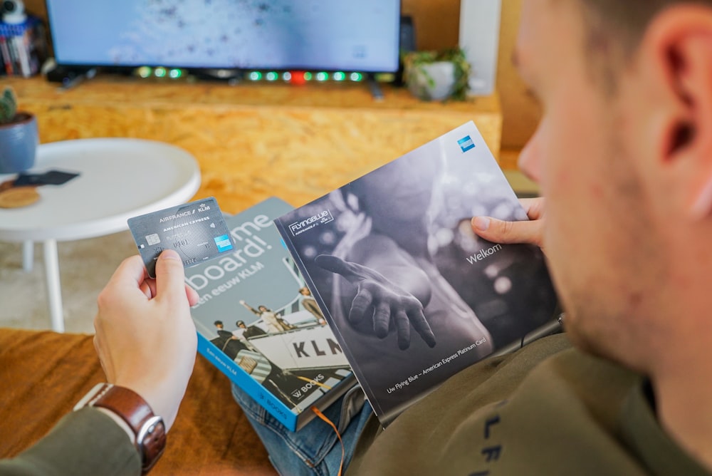 a man reading a book in front of a tv