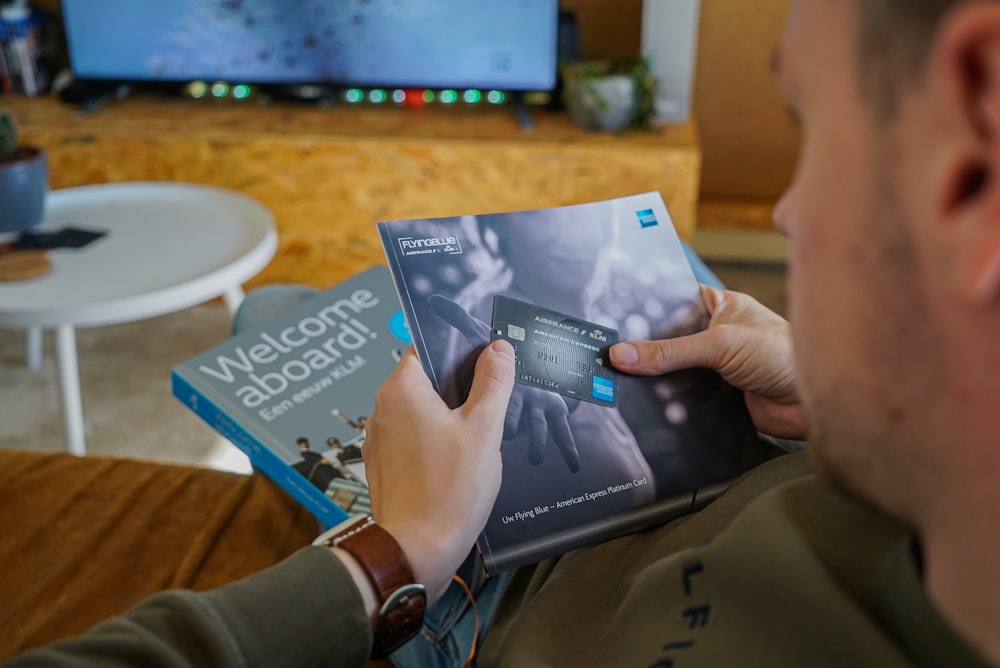 a man reading a book in front of a television