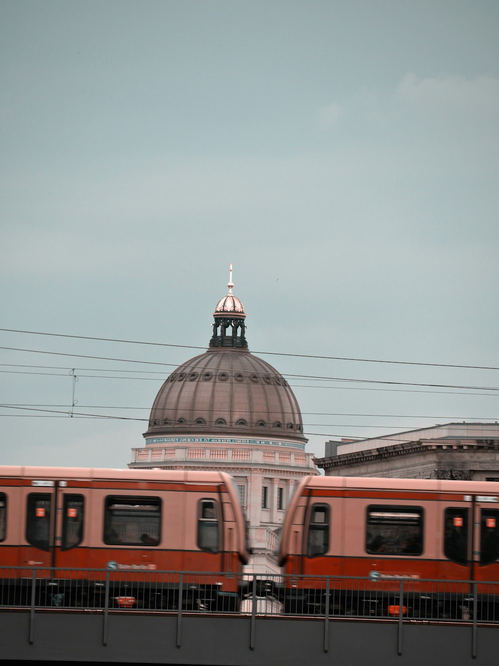 a red train traveling past a tall white building