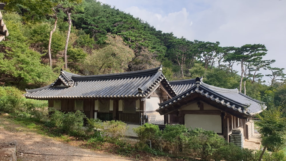 a building with a black roof sitting on top of a lush green hillside