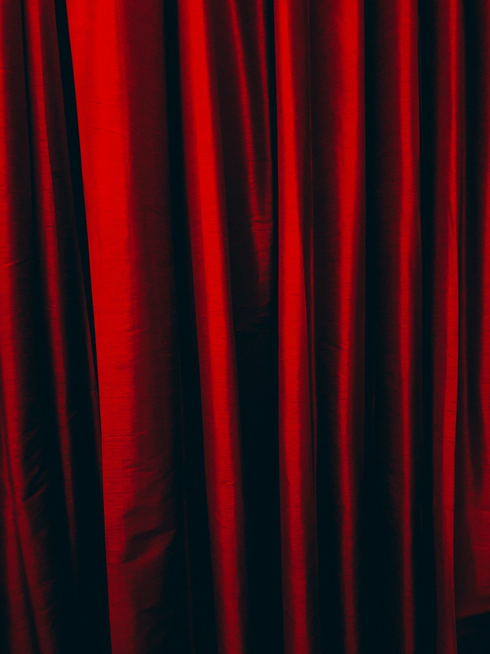 a close up of a red curtain with a black background