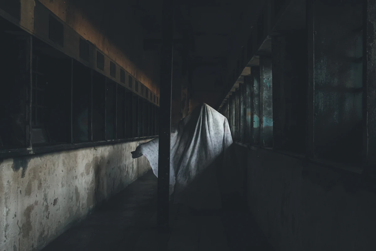 A dark, sparse room with a sheet on the wall