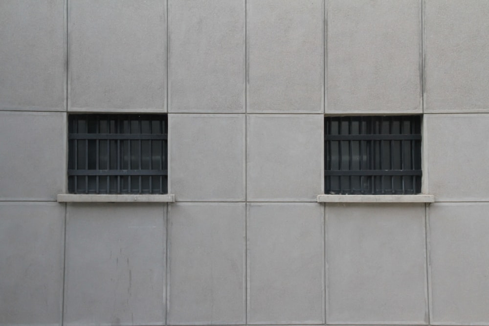 un edificio con dos ventanas y rejas en el lateral