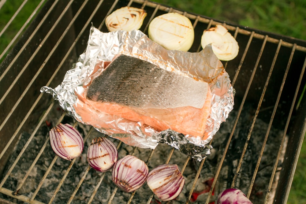 a piece of salmon on a grill with onions and garlic