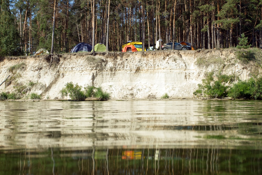 Un groupe de tentes assises au sommet d’une falaise à côté d’un plan d’eau