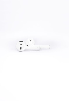 A pair of white wireless AirPods displayed against a clean, minimalist background.