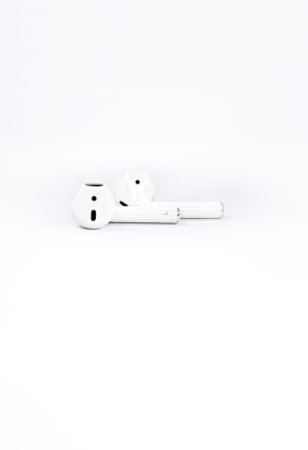 Two white wireless earbuds placed on a plain white background, highlighting their sleek and minimalistic design.