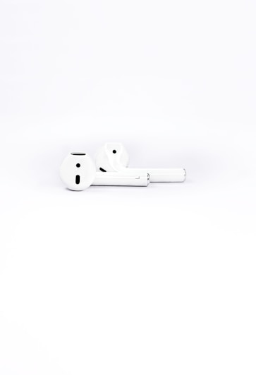 Two white wireless earbuds placed on a plain white background, highlighting their sleek and minimalistic design.