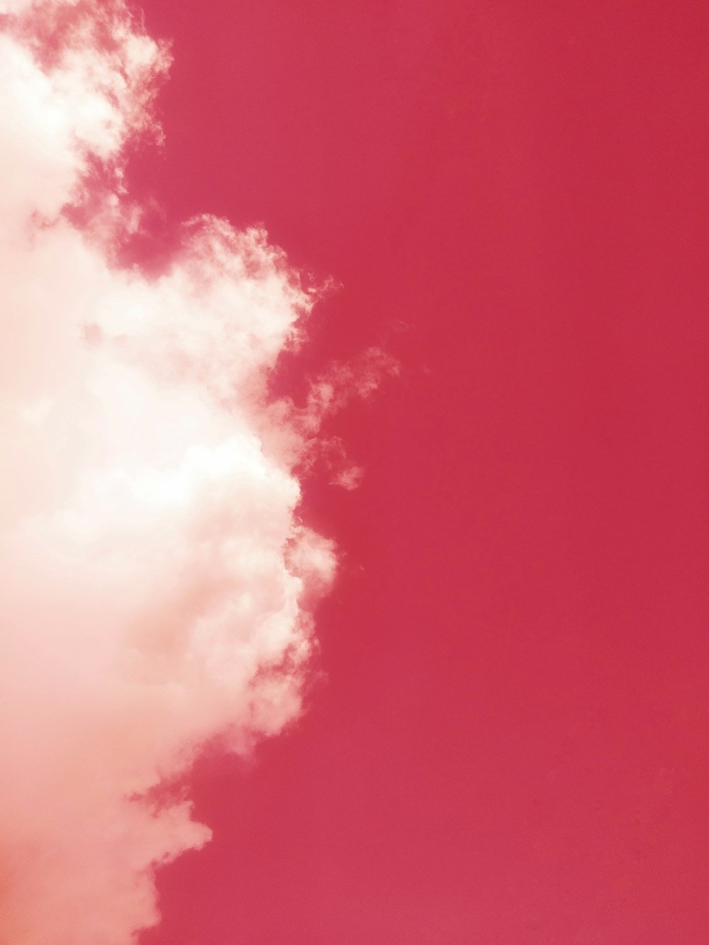 a plane flying through a pink sky with clouds
