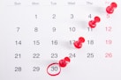 a calendar with red push buttons pinned to it