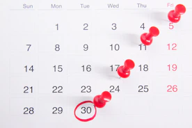 a calendar with red push buttons pinned to it