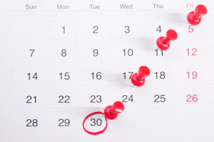 a calendar with red push buttons pinned to it
