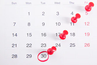 a calendar with red push buttons pinned to it