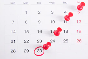 a calendar with red push buttons pinned to it