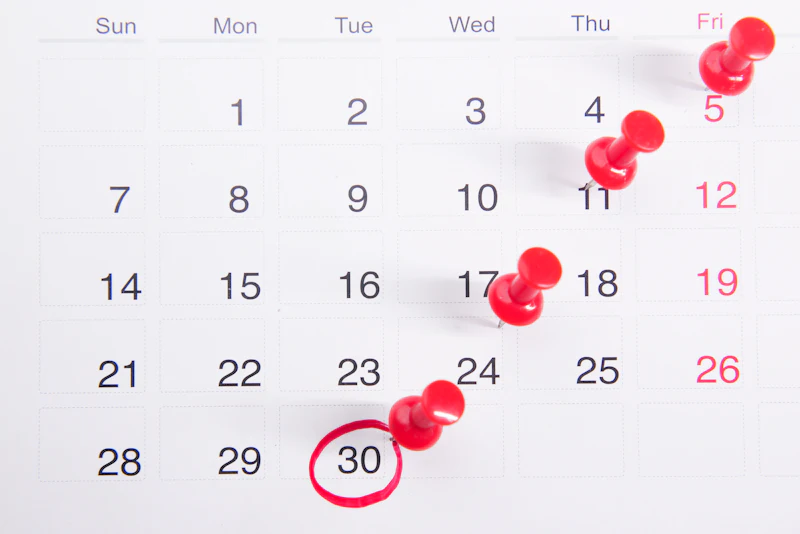 A calendar with red push pins on it