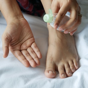 a person with a bottle on their foot on a bed