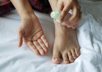 a person with a bottle on their foot on a bed