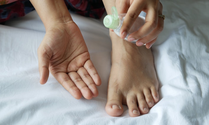 a person with a bottle on their foot on a bed